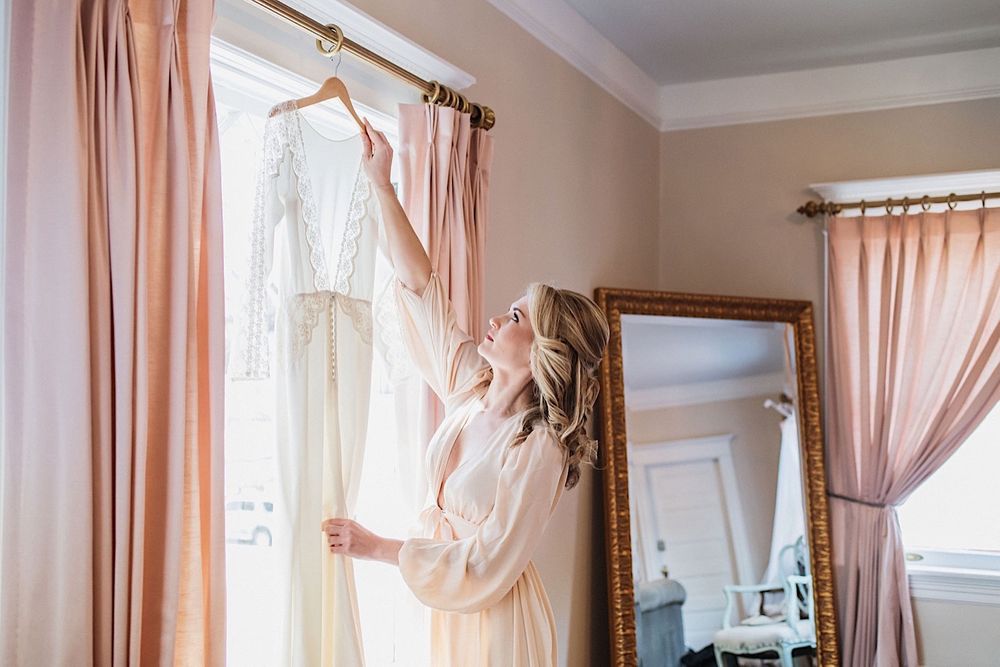 Bride in a silk robe reaching for her wedding dress