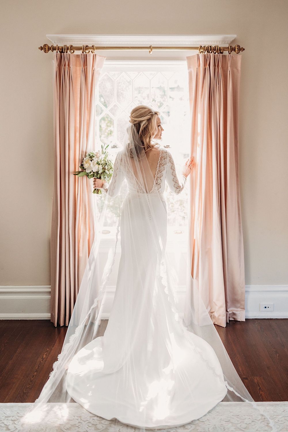 Bride in BHLDN wedding dress standing in the window