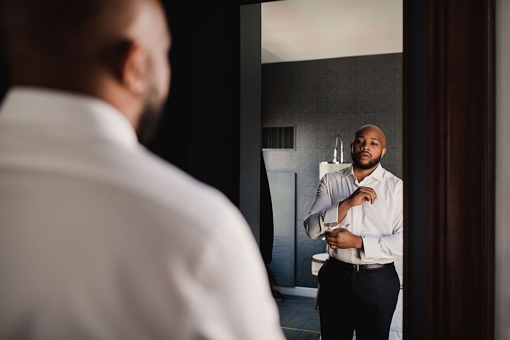 groom looking in the mirror at Le Meridien Hotel in Tampa as he gets dressed
