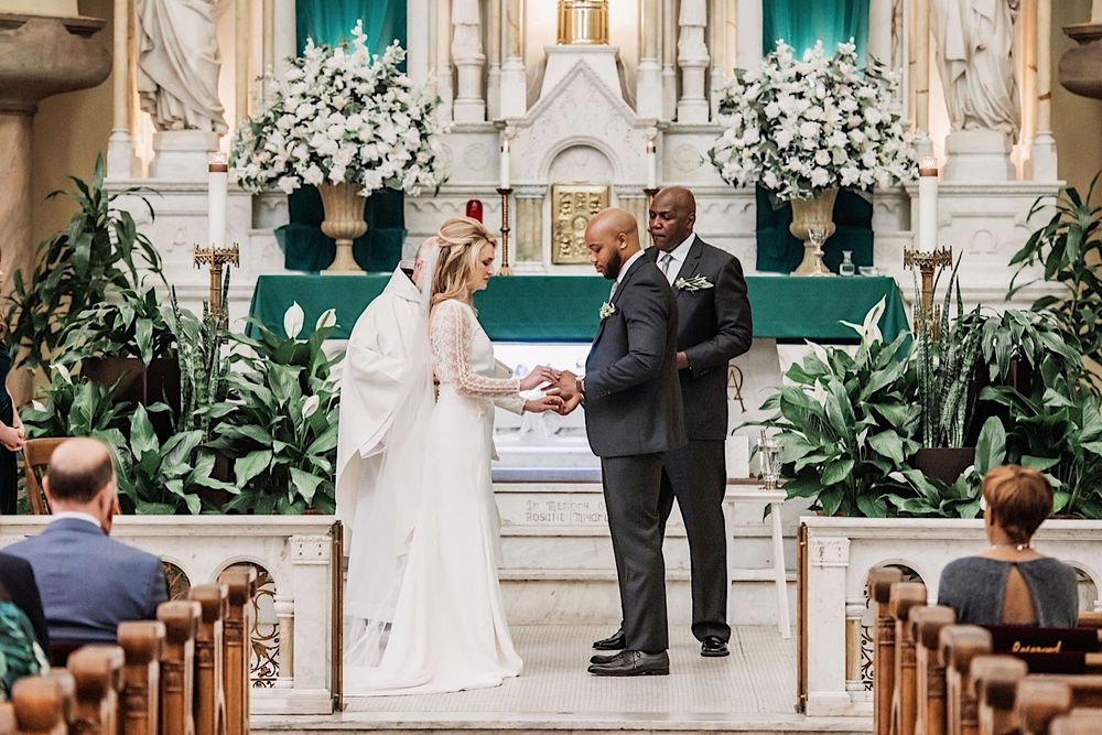 bride and groom exchanging rings at the altar at sacred heart church