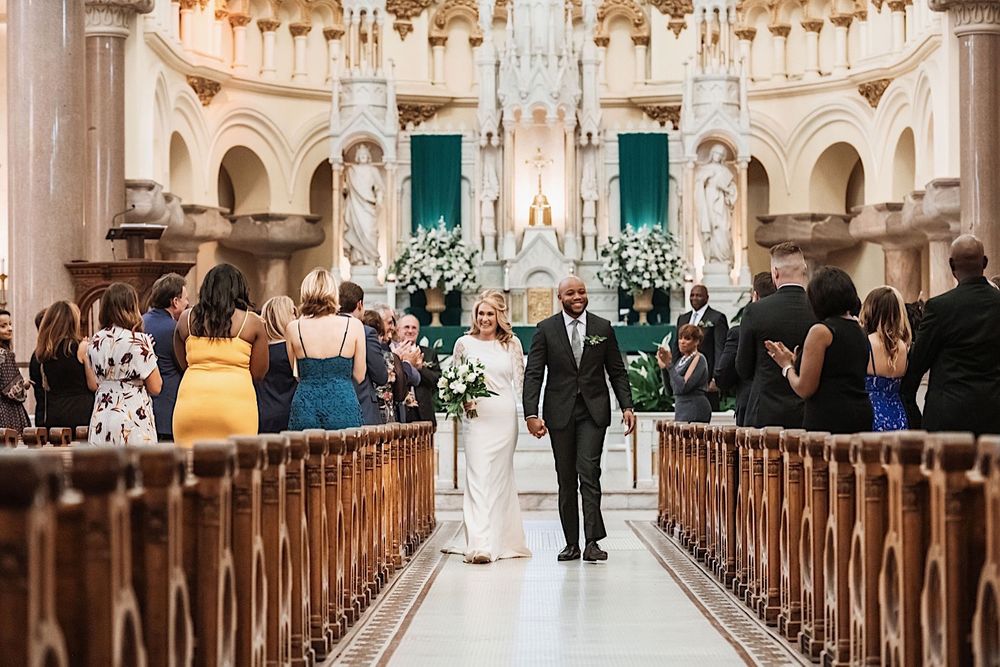 bride and groom walking down the aisle during the recessional at sacred heart church