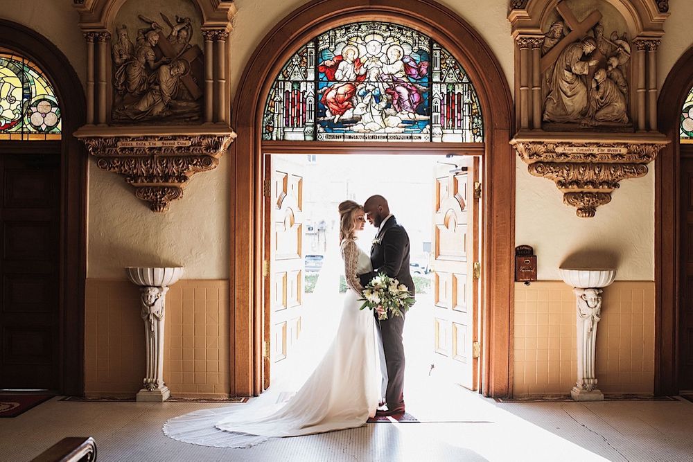 Bride and groom posing with foreheads touching in the entrance of sacred heart church in Tampa