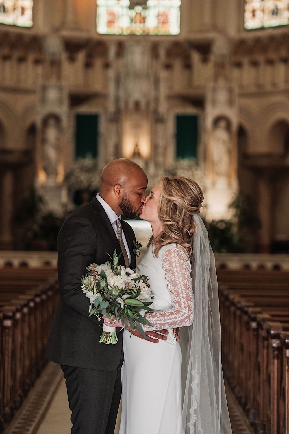 bride and groom standing in sacred heart church and kissing