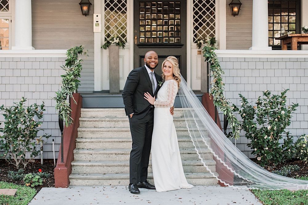 Bride and groom standing in front of the stairs at the Orlo and smiling for the camera