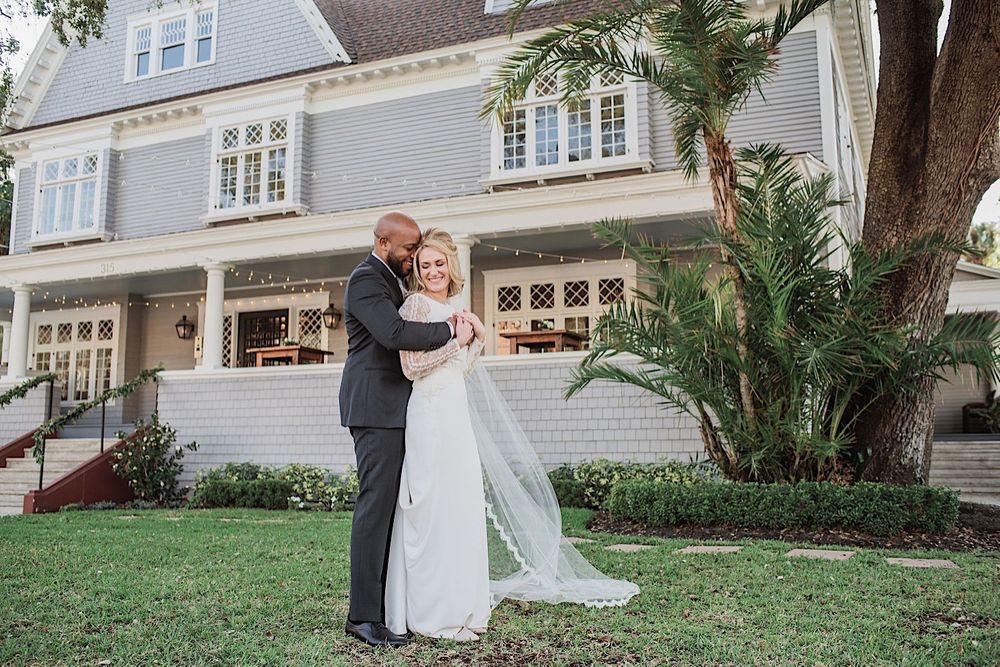 groom hugging bride in the front yard of the oral wedding venue