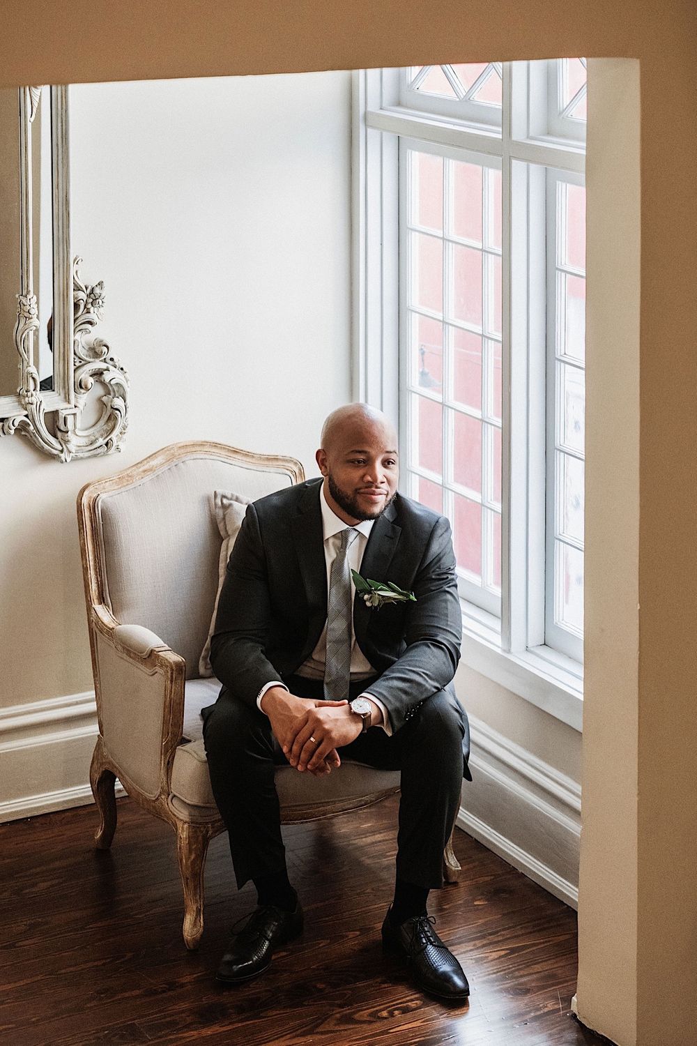 Groom sitting in chair wearing a black suit