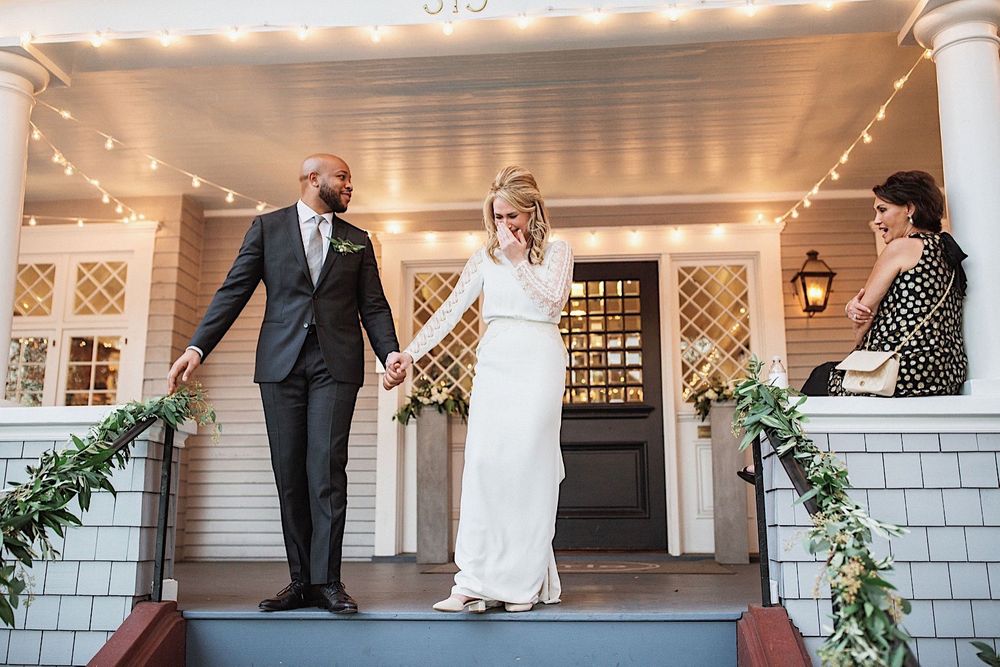 bride and groom holding hands and walking down the stairs being surprised and emotional