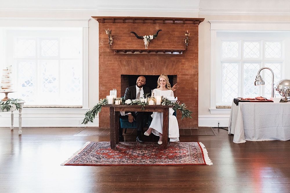 bride and groom sitting at the sweetheart table and laughing at their wedding