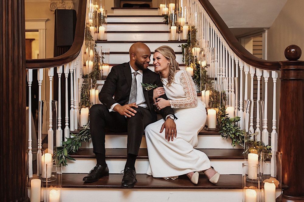 bride and groom sitting on the stairs with candles and greenery at the Orlo in tampa