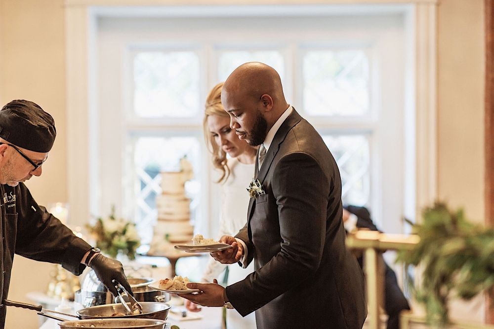 bride and groom serving themselves food at the buffet