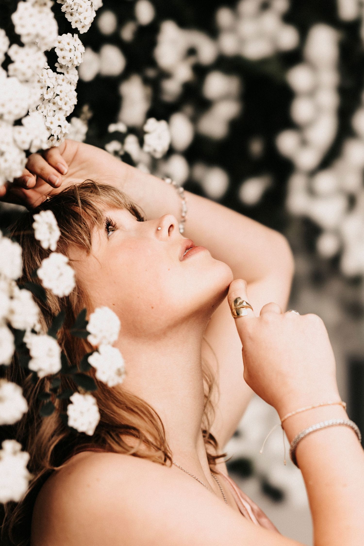 Dreamy portrait among white cherry blossoms with soft bokeh effect.
