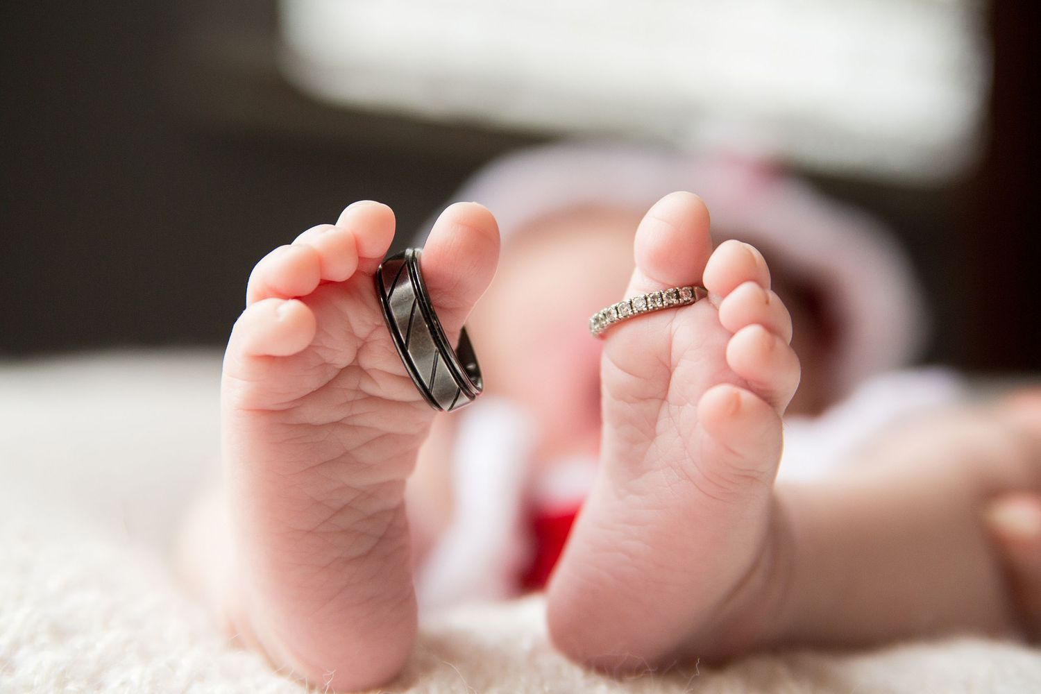 Newborn baby feet with the mom and dad's wedding rings placed around their big toe.
