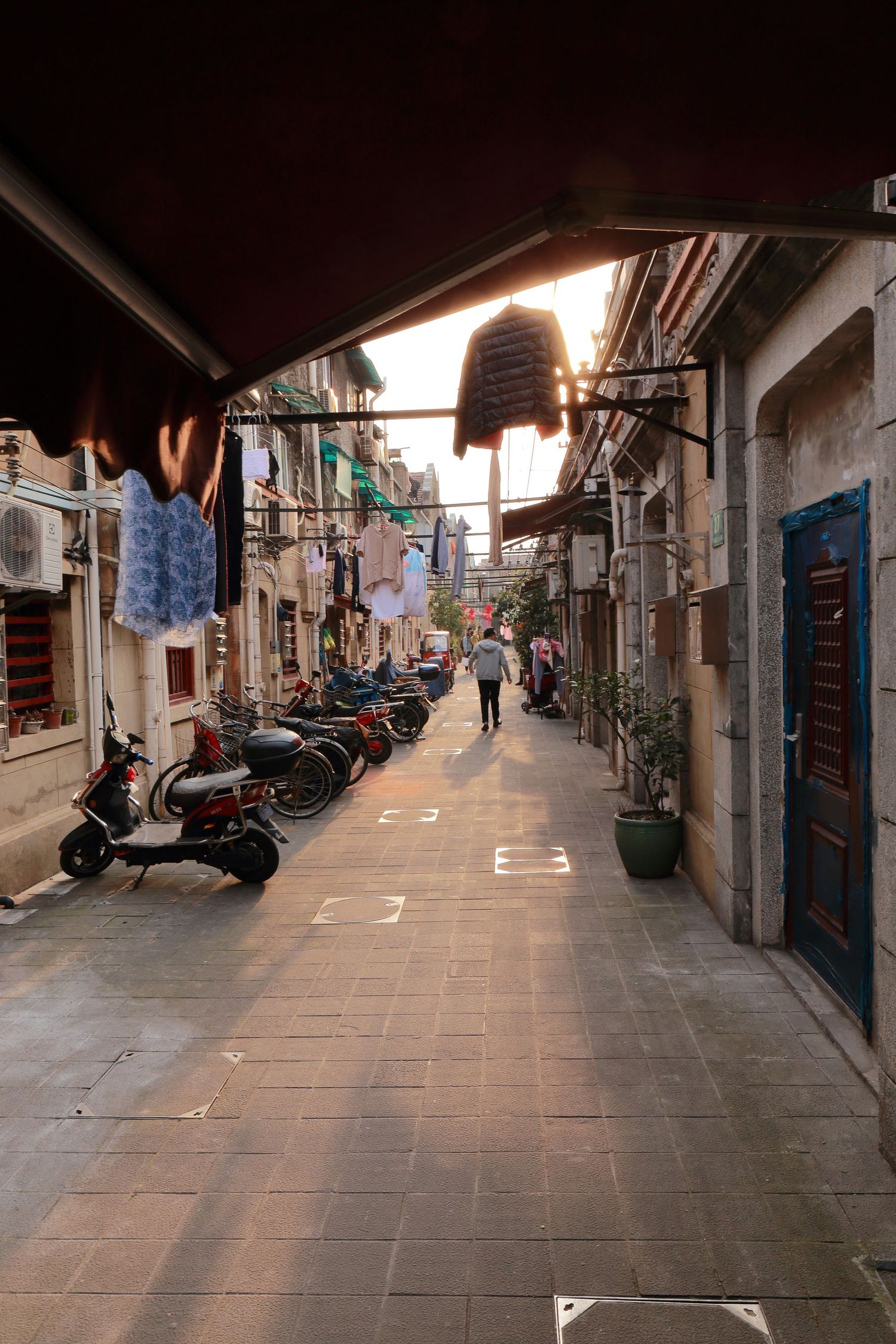 Narrow alley in Shanghai with parked scooters and hanging laundry.