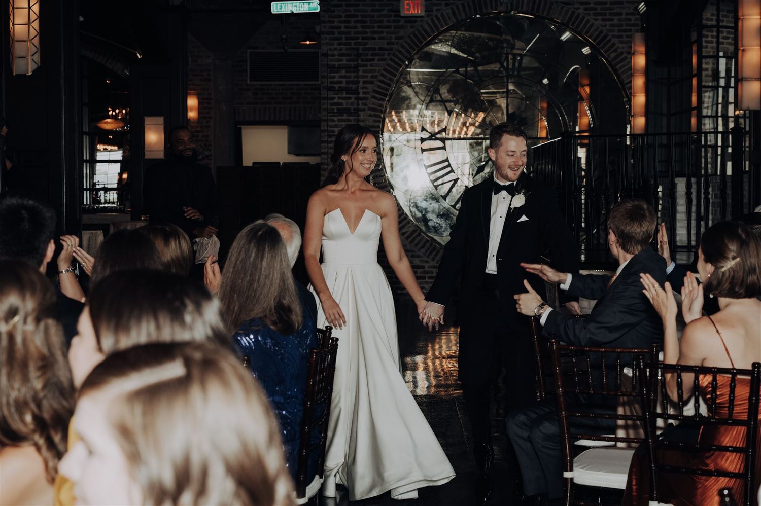 Couple makes grand entrance at wedding reception with guests celebrating.