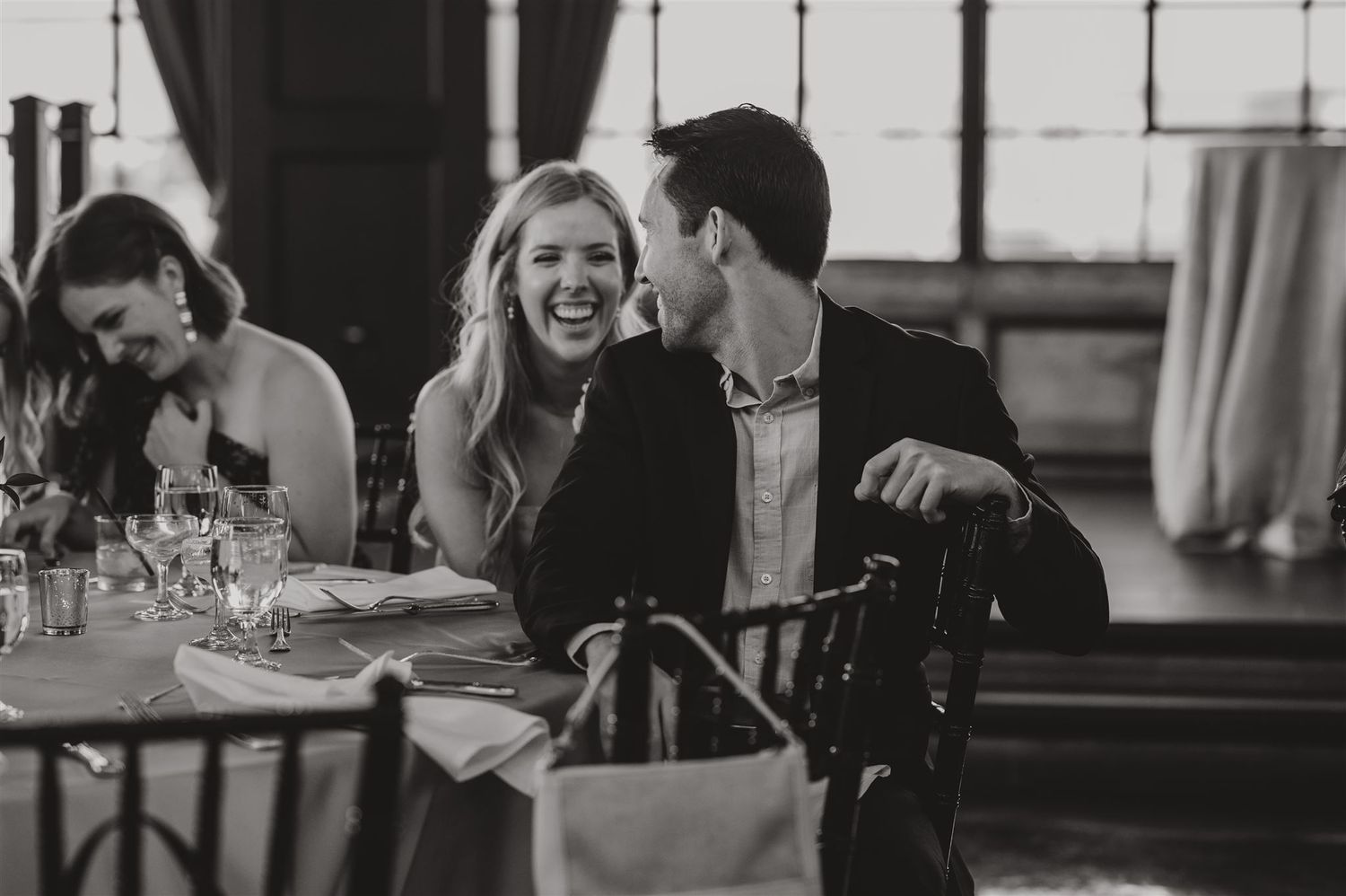 Wedding guests share laughter during reception dinner party.