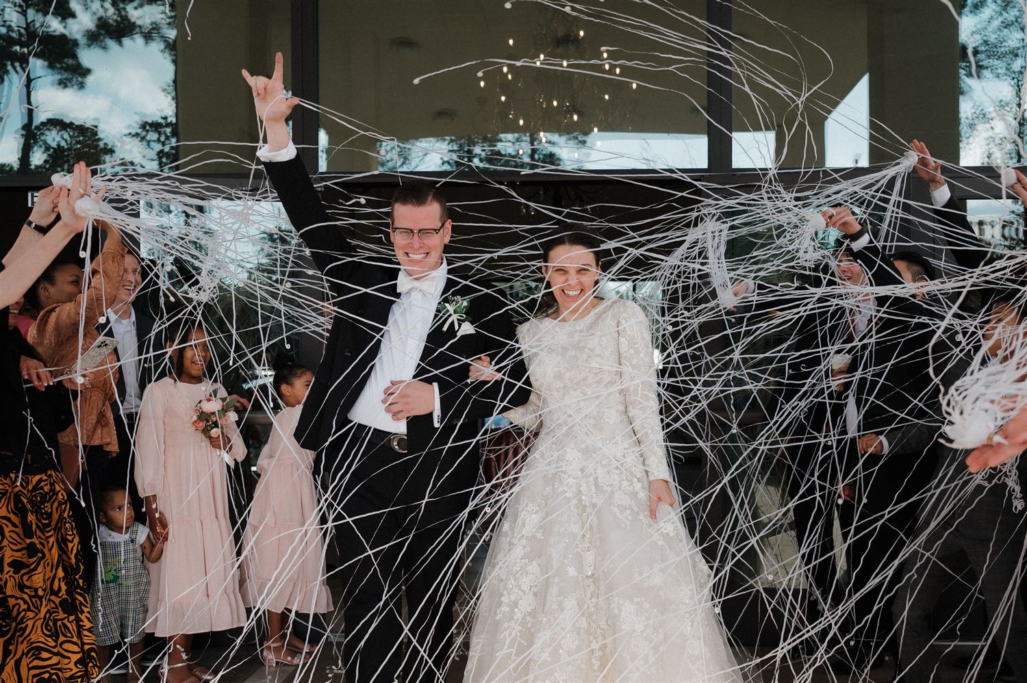 Wedding couple celebrates under dramatic streamer display with guests.