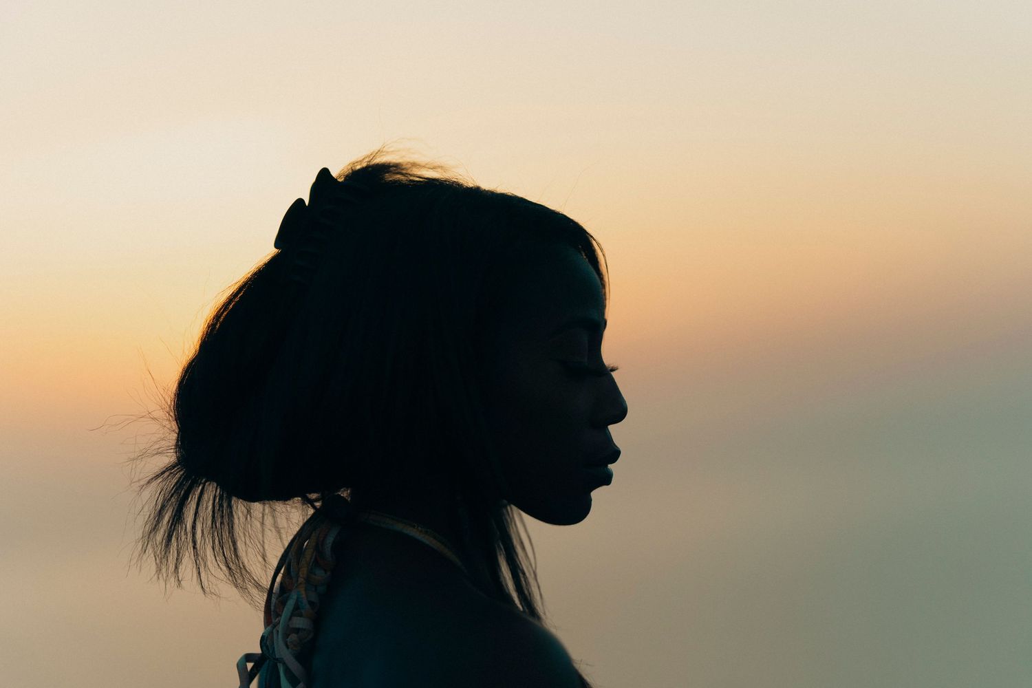 Silhouette of a person's profile against a warm sunset sky creating a dramatic contrast.