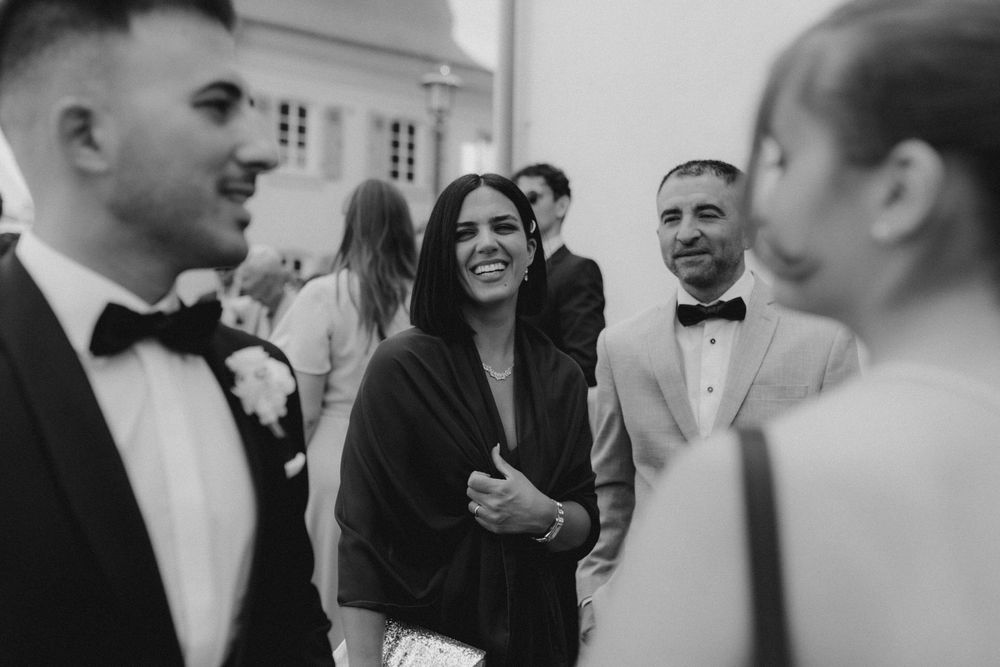 Black and white photo of wedding guests in formal attire gathered at an elegant reception.