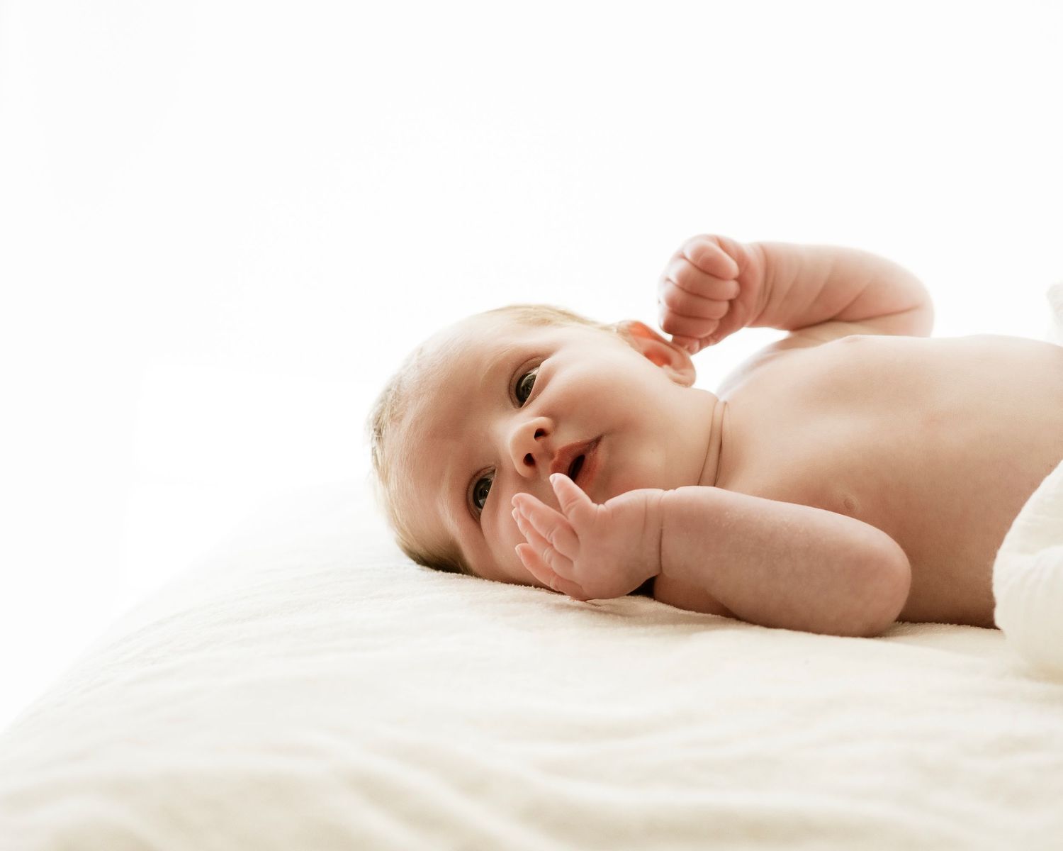 baby lying on bed in softly lit room during a relaxed Sydney North Shore session