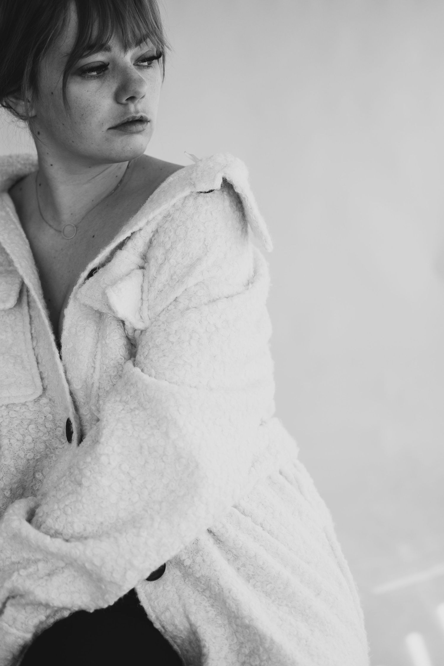 Monochrome portrait showing person in cozy white knit sweater looking to the side.