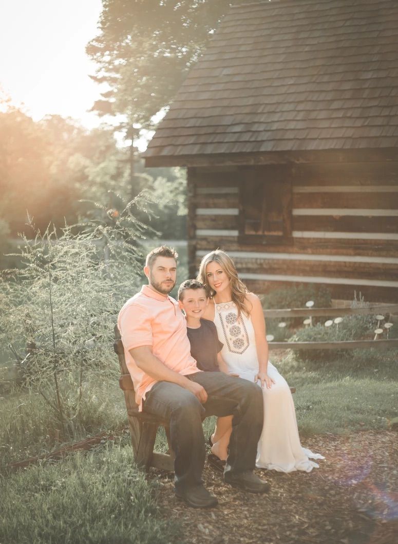 A family portrait taken at sunset in front of a rustic log cabin.
