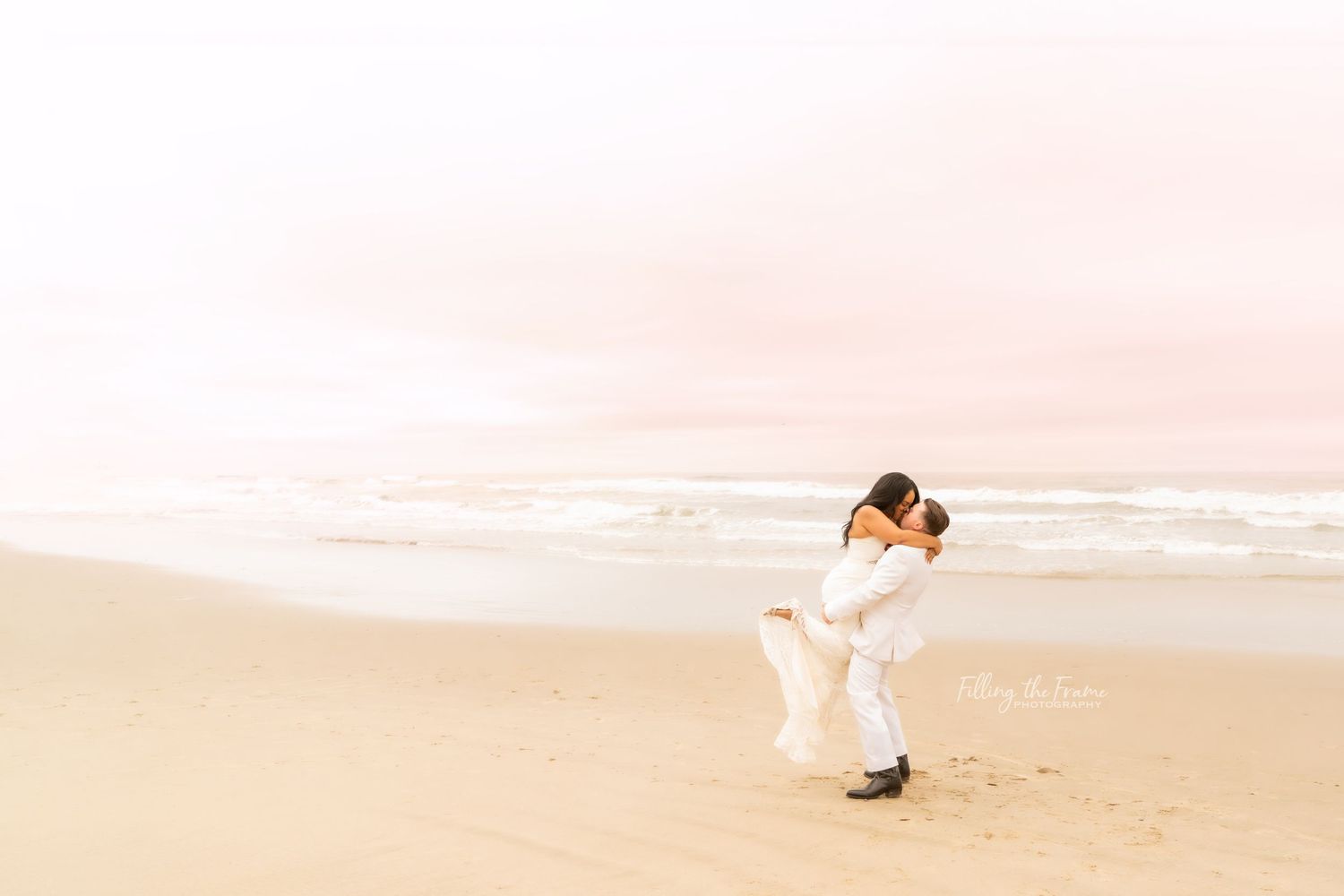 A romantic moment between a couple on a misty beach at sunset.