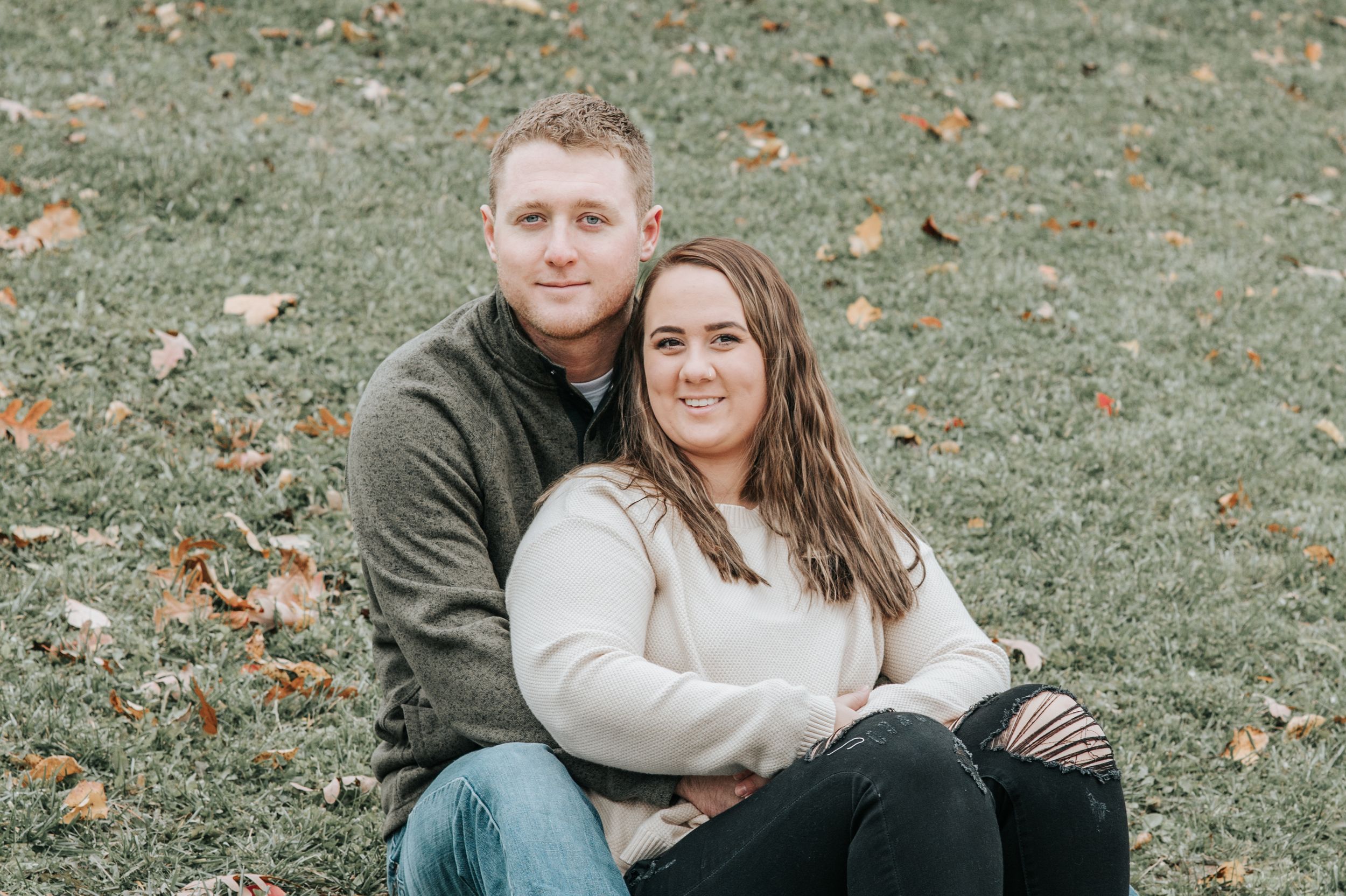 Casual outdoor portrait session of couple sitting together on grass.