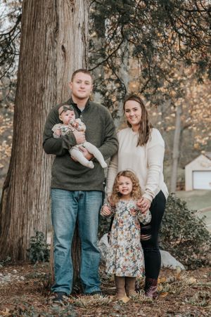 Family portrait session among tall trees with autumn foliage.