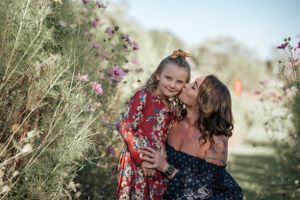 Candid family photoshoot in a field of blooming wildflowers at sunset.