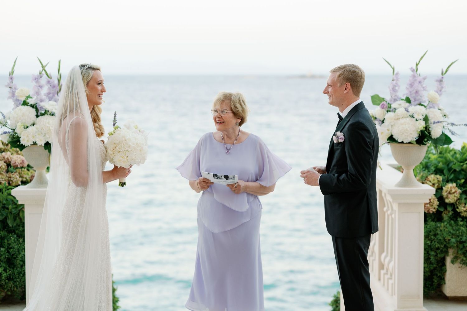 Oceanfront wedding ceremony with white floral arrangements and elegant decor.