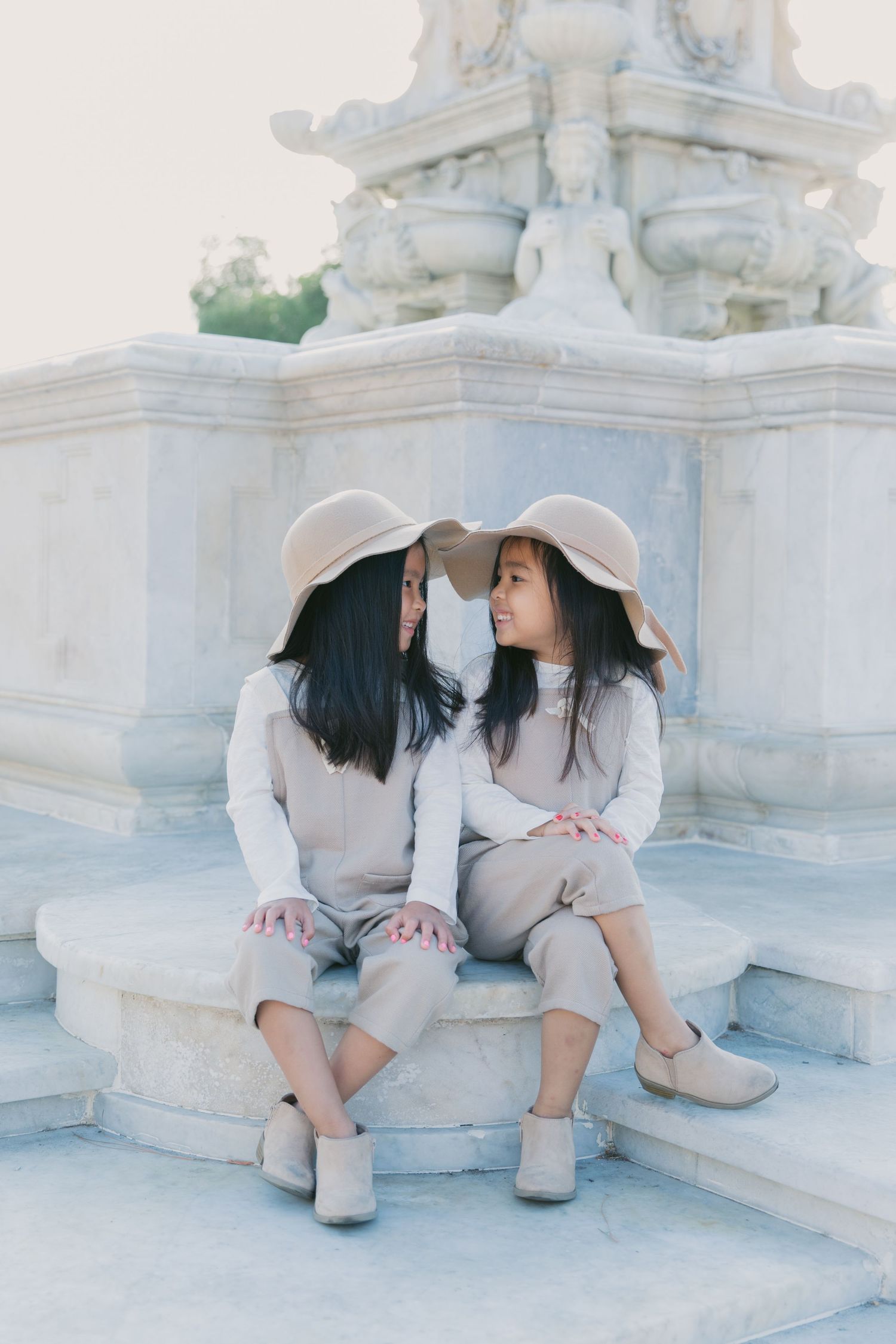 Two people in matching outfits sitting on white stone steps outdoors.
