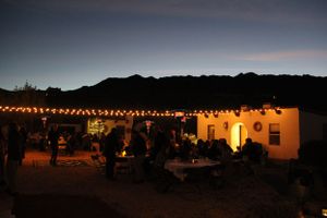 String lights illuminate outdoor wedding reception area against desert backdrop at night.