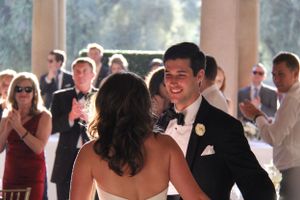 A couple shares their first dance at an elegant wedding reception under arched columns.