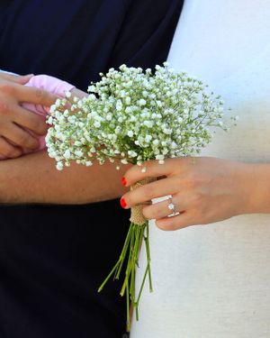Delicate baby's breath bouquet held in hands with an engagement ring visible.