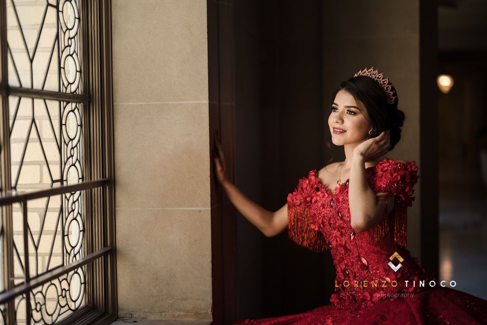 Red formal dress with embellishments photographed by ornate window.