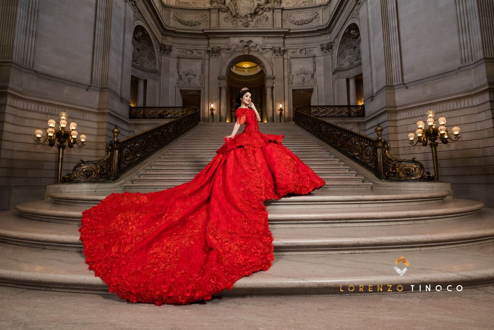 Stunning red ball gown with long train photographed on grand marble staircase.
