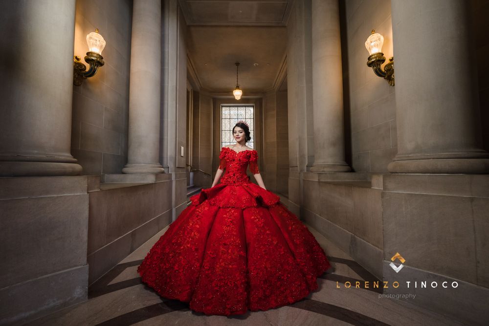 Elegant red ball gown photographed in classical corridor with wall sconces.