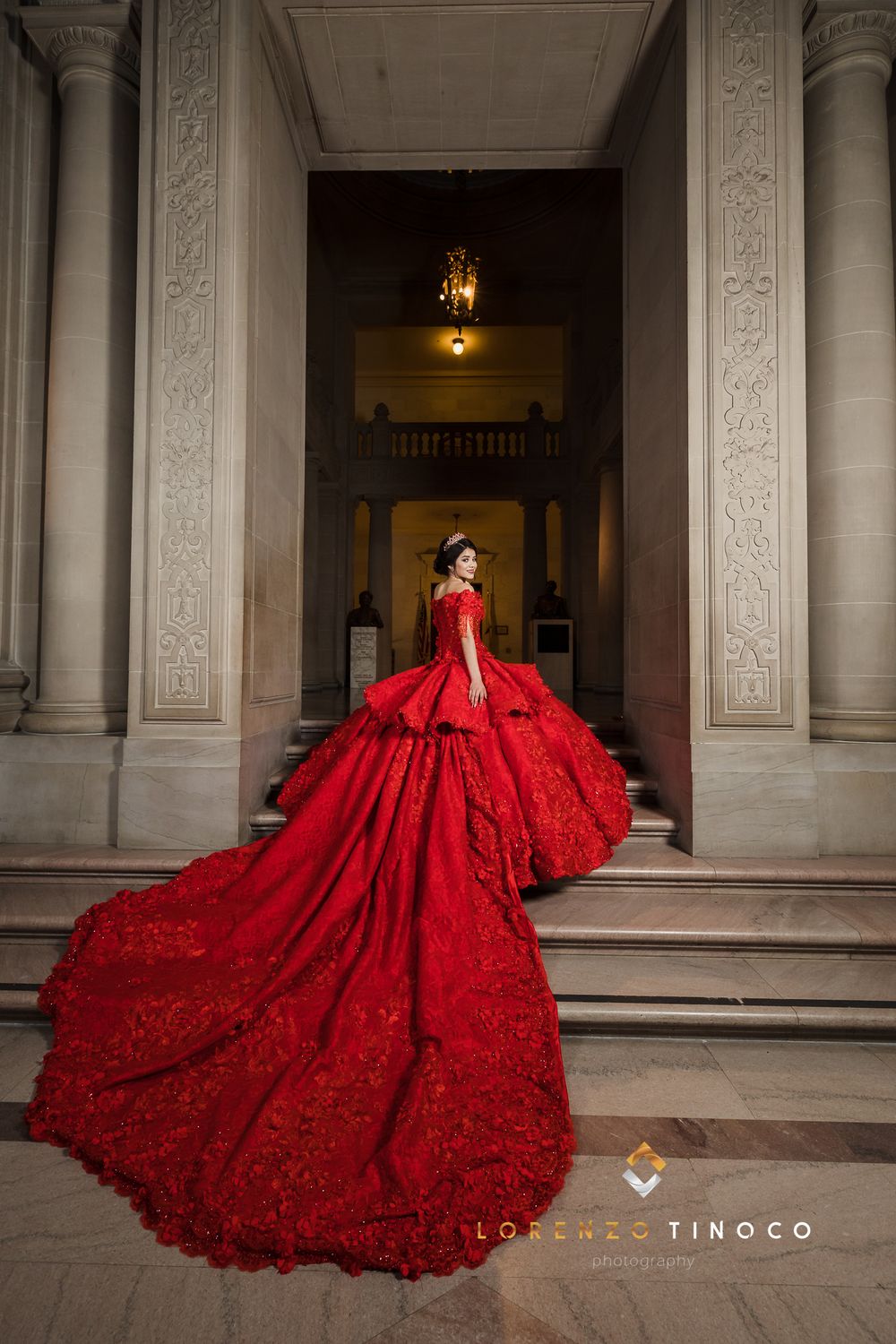 Red ballgown with dramatic train photographed on marble staircase.