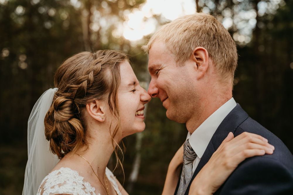 Intimate sunset wedding portrait of a couple sharing a tender moment in a forest.