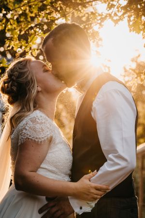 Romantic sunset wedding portrait with golden sunlight filtering through trees.