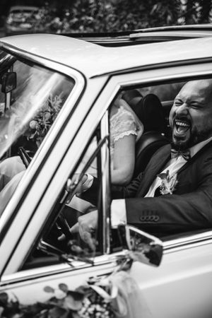 Black and white photo of joyful moments inside a classic car.