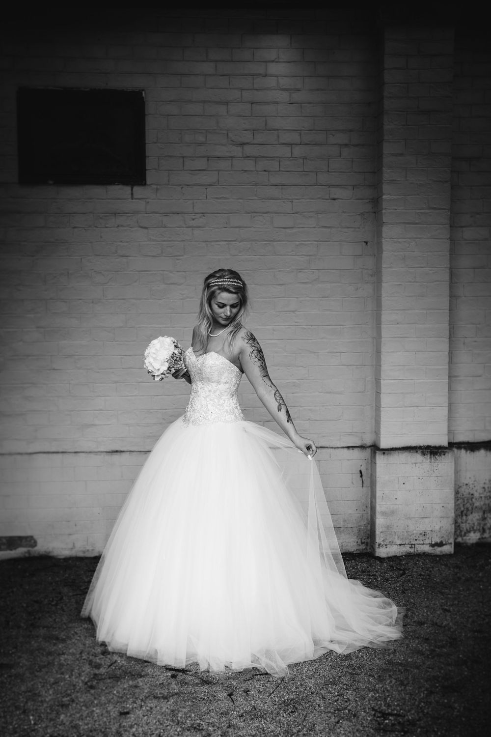 Artistic black and white photos of a wedding dress against white brick wall.