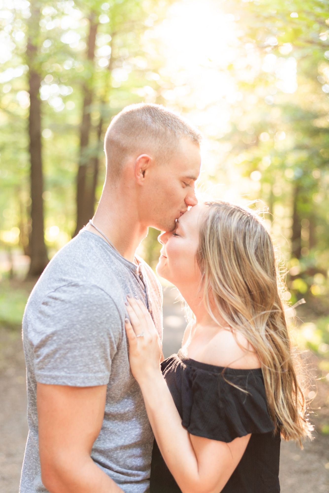 Boy kissing girl's forehead in forest for engagement in St. Mary's Pennsylvania