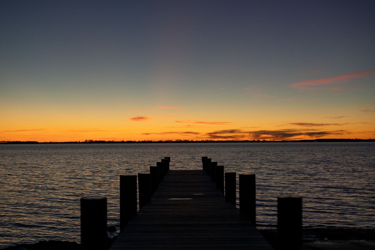 Beautiful orange and purple sunset over calm water horizon view.