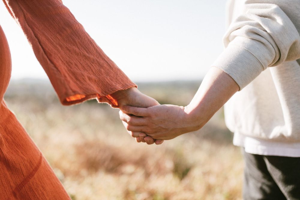 Close-up of hands holding tenderly against backdrop of golden field.