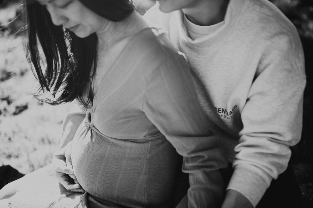 Black and white intimate maternity photo showing gentle embrace and baby bump.