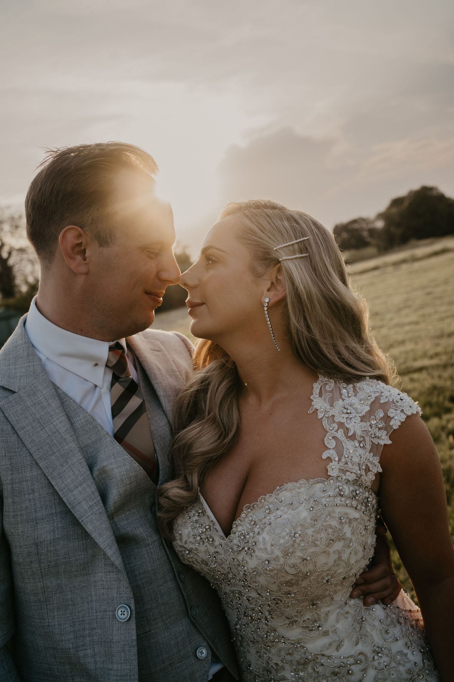 A bride and groom almost kissing during golden hour.  The sun shining on them.