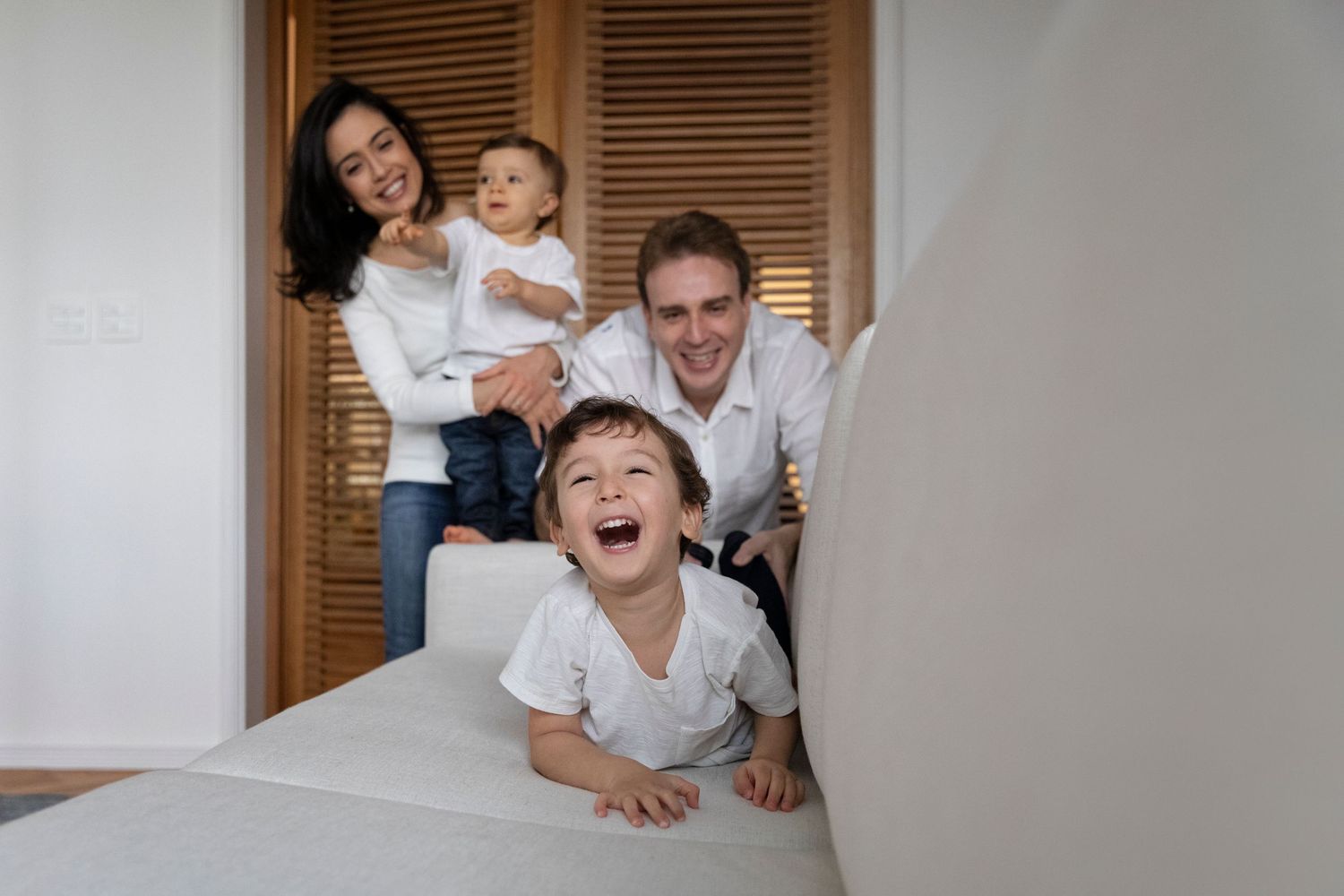 A candid family photo showing pure joy and laughter near wooden doors.