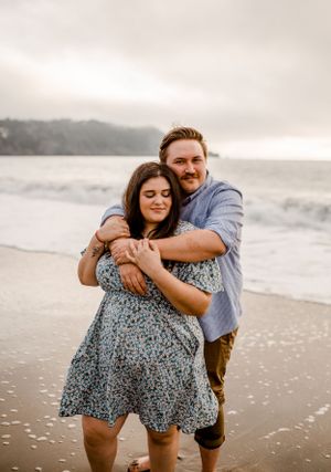 A couple embraces lovingly on a foggy beach during an intimate photoshoot near the ocean.