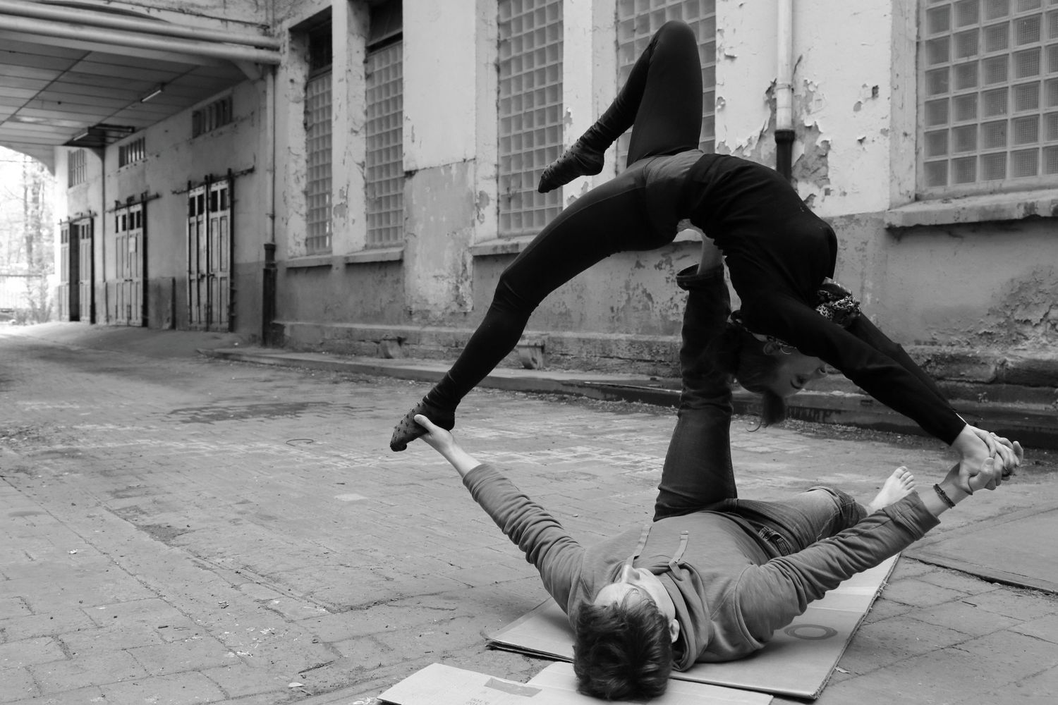 Black and white photo of two dancers performing acrobatic moves on the street.